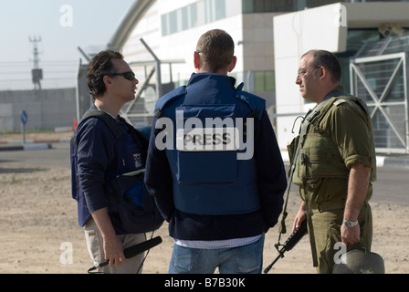 TV News crew wearing protective flak jacket marked 'TV' speaking with Israeli military spokesperson near Gaza border Stock Photo