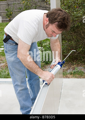 Handyman using a caulking gun to caulk a home improvement project Stock Photo