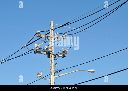 Telephone and electric pole with wires insulators cables and street lamp Stock Photo