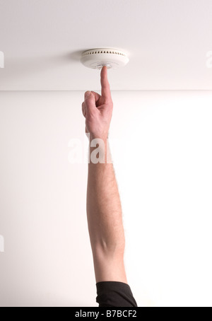 Man testing a domestic fire alarm is working correctly Stock Photo