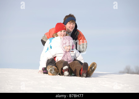 15, 13 and 9 year olds prepare to slide down hill, Winnipeg, Canada Stock Photo