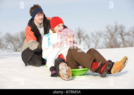 15, 13 and 9 year olds prepare to slide down hill, Winnipeg, Canada Stock Photo