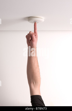 Man testing a domestic fire alarm is working correctly Stock Photo