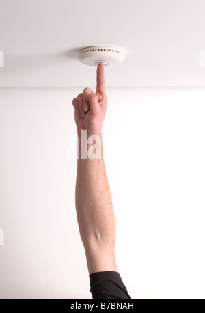 Man testing a domestic fire alarm is working correctly Stock Photo