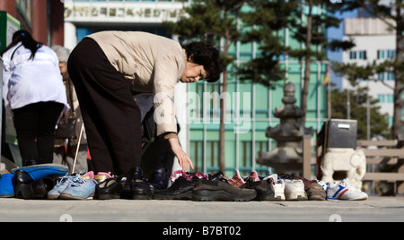 Woman removing her shoes outside Hall of the Great Hero, Jogyesa Temple, Seoul, South Korea Stock Photo