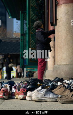 Woman praying outside Hall of the Great Hero or Daeung jeon at Jogyesa Buddhist Temple, Seoul, South Korea Stock Photo