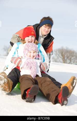 15, 13 and 9 year olds prepare to slide down hill, Winnipeg, Canada Stock Photo