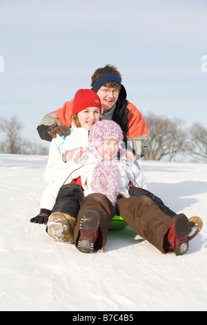 15, 13 and 9 year olds prepare to slide down hill, Winnipeg, Canada Stock Photo