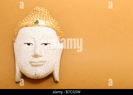 handcrafted wooden buddha decorative mask on yellow background with copyspace Stock Photo