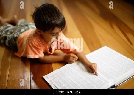 Six year old boy points to index of atlas Stock Photo