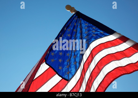 The American flag hangs proudly with a blue sky background on Main Street in Hometown America Stock Photo