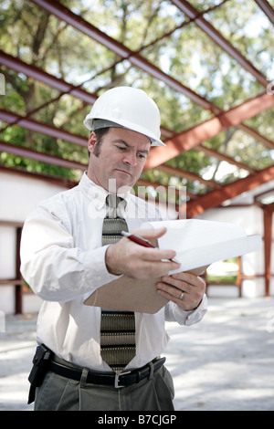 A building inspector on site reviewing his notes Vertical view Stock Photo