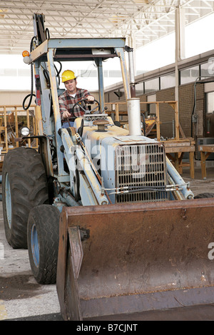 A man on a construction site driving a backhoe loader Stock Photo