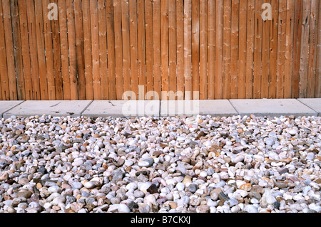 A wooden fence, concrete path and many small stones. Horizontal Stock Photo