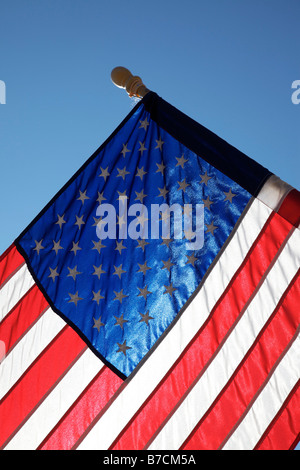 The American flag hangs proudly with a blue sky background on Main Street in Hometown America Stock Photo