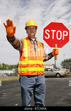 A construction worker holding a stop sign and directing traffic Stock Photo