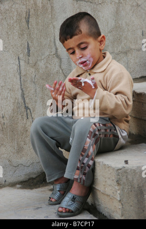 Kurdish boy eating ice cream and with dirty hands, Iraq, Iraqi Kurdistan, Sulaimaniyya, Sulaymaniyah Stock Photo