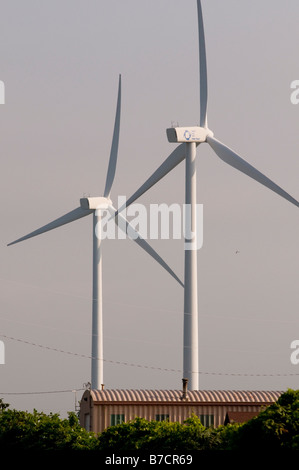 Commercial wind turbines rise above a corrugated metal building Stock Photo