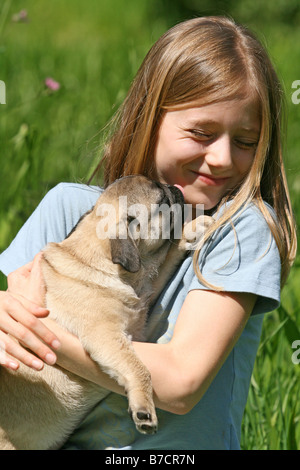 Pug (Canis lupus f. familiaris), girl with Pug whelp in her arms Stock Photo