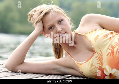 young blond woman lying on a landing stage Stock Photo