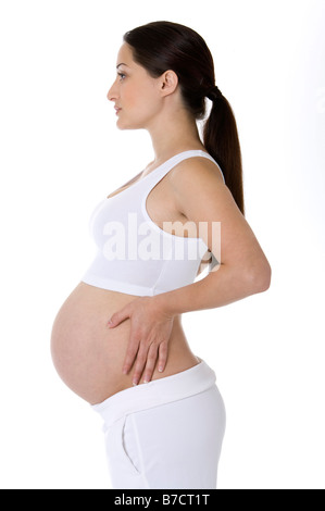 Pregnant young woman standing hand on hip profile Stock Photo