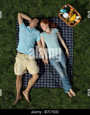A young couple sleeping on a blanket in the park Stock Photo