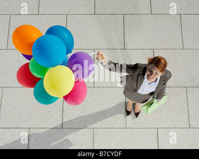 A young woman holding a bunch of balloons Stock Photo