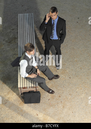 Two businessmen waiting by a bench Stock Photo