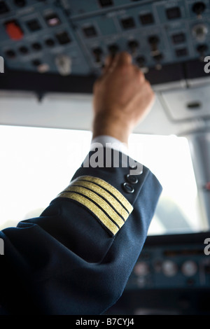 A pilot's hand using the control panel in the cockpit of a commercial airplane Stock Photo