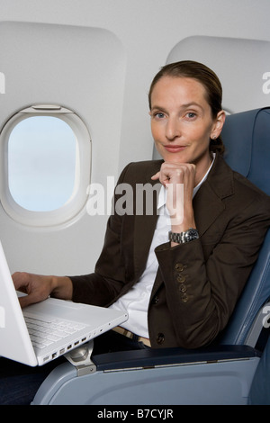 A businesswoman working on a laptop on a plane Stock Photo