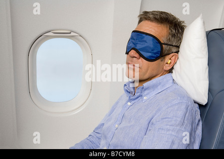 A man wearing a sleep mask sleeping on a plane Stock Photo