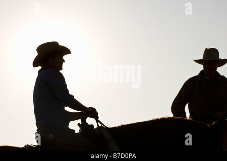 Silhouette of two cowboys sitting on horses Stock Photo