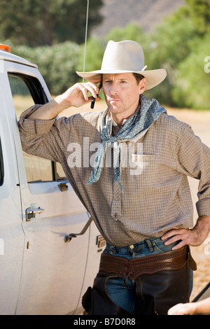 A cowboy leaning against his car and talking in his mobile phone Stock Photo