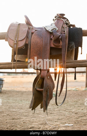 A saddle hanging on a fence Stock Photo