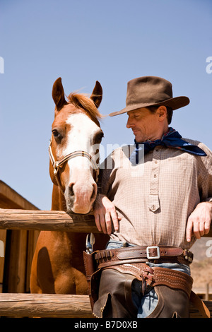 Portrait of cowboy standing next to a horse Stock Photo