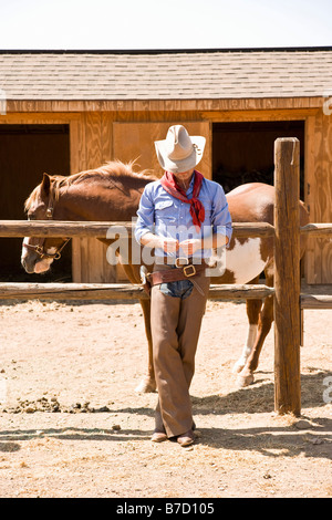 A cowboy leaning against a fence on a ranch