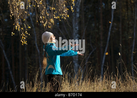 A young girl in a field catching leaves Stock Photo