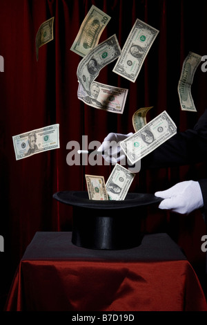 A magician performing magic by making money come out of a hat Stock Photo