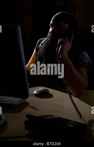 A biker sitting in a darkened office on the phone Stock Photo