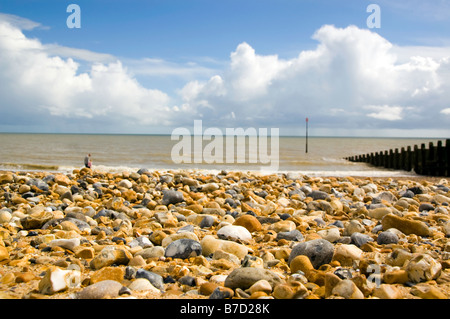 Pebble beach on a summer's day with white fluffy clouds Stock Photo
