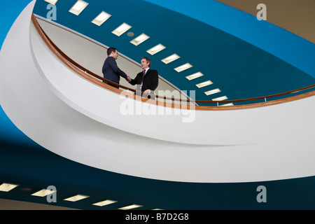 Two businessmen standing on a balcony and shaking hands Stock Photo