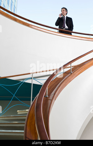 A businessman talking on his mobile phone at the top of a staircase Stock Photo