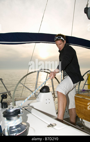 A man pulling the rigging on a yacht Stock Photo