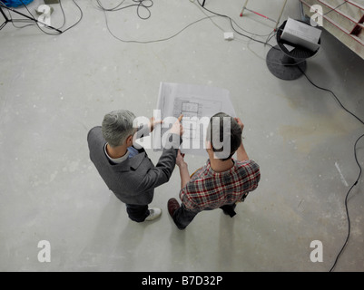 A construction worker going over blueprints with an architect Stock Photo