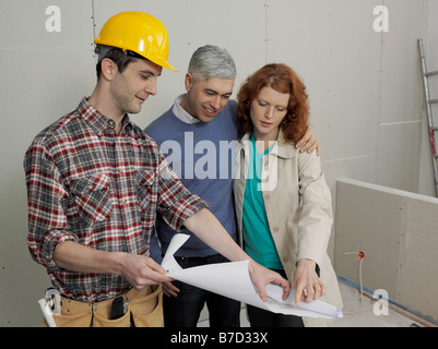 A building contractor going over blueprints with a young couple Stock Photo