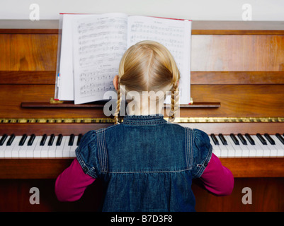A little girl playing a piano, rear view, portrait Stock Photo