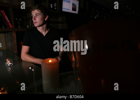 a portrait of a young attractive male barman pulling a pint in a trendy bar in london. he is smiling and looking at the camera Stock Photo