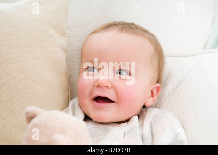 A baby smiling holding a bear Stock Photo