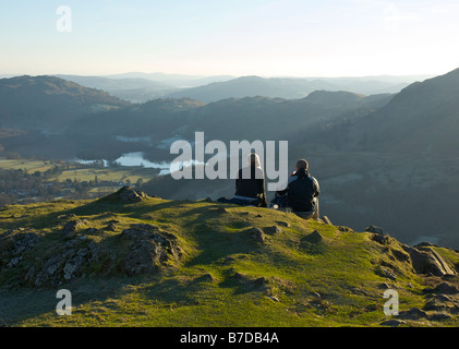 Two walkers on Helm Crag, enjoying the view over Grasmere, Lake District National Park, Cumbria, England UK Stock Photo