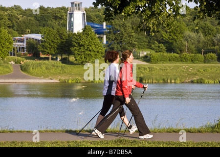 two women during nordic walking at the Kemnade Storage Lake, with the freetime center Kemnade in the background, Germany, North Stock Photo